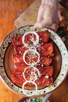 a plate filled with meat covered in sauce and onions on top of a wooden table