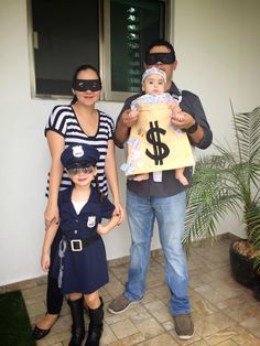 two adults and one child are wearing masks while holding a bag with a dollar sign on it