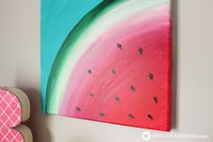 a watermelon painting hanging on the wall next to a pink and green letter b