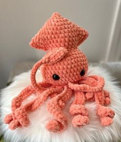 an orange crocheted octopus stuffed animal sitting on top of a white fluffy pillow