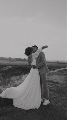 a bride and groom kissing in the middle of an open field on their wedding day