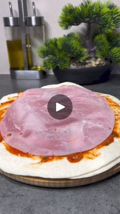 an uncooked pizza with ham on it