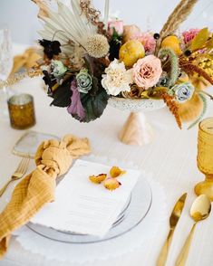 the table is set with an elegant centerpiece and napkins, along with gold cutlery