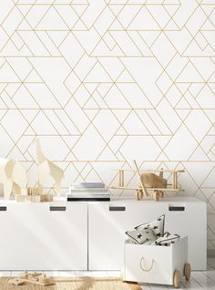 a white dresser with gold geometric wallpaper and wooden toys on it in a living room