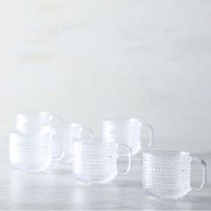 five glass mugs lined up on a table