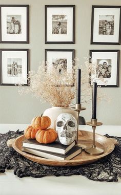 a tray with candles, skulls and pumpkins on it in front of framed pictures