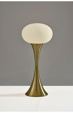 a gold table lamp with a white glass shade on it's top and bottom