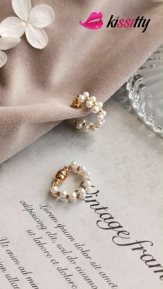 two pearls are attached to the end of a pair of earring studs on top of a piece of paper