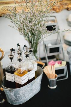 an assortment of liquor bottles in a metal container on a black table with silver trays