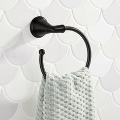 a towel hanging on the wall next to a black scallop style shower faucet