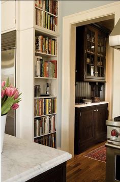 a vase with flowers in it sitting on a kitchen counter next to a stove top oven