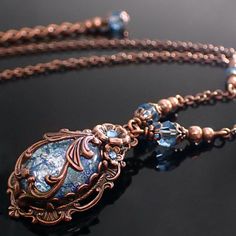 "To make this Victorian style necklace, I wrapped an aqua blue glass faux opal cabochon in exquisitely detailed antiqued copper filigree. The stone is set in an antique Victorian style setting and adorned with floral elements and coordinating crystals. --------------------------------------------------------------------------------------------- Dimensions and details - Focal cabochon measures 18x13mm - The drop of the entire pendant (top of setting to bottom of setting) is approximately 1 and 3/ Elegant Copper Filigree Jewelry, Elegant Gemstone Copper Jewelry, Elegant Bronze Copper Jewelry, Vintage Bronze Filigree Jewelry, Bronze Filigree Jewelry For Vintage Collection, Antique Blue Necklace With Intricate Design, Elegant Bronze Cabochon Jewelry, Elegant Bronze Collectible Necklace, Oval Bronze Jewelry With Intricate Design