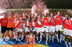 a group of men standing on top of a soccer field holding a trophy and confetti