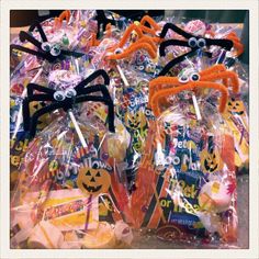 halloween treats wrapped in plastic and decorated with spider faces, candy sticks and candies