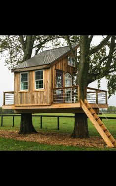 a tree house built on top of a wooden platform in the middle of a field