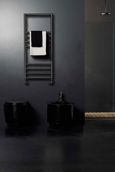 a black bathroom with two toilets and a shower