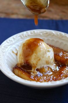 a white bowl filled with ice cream and caramel on top of a blue table