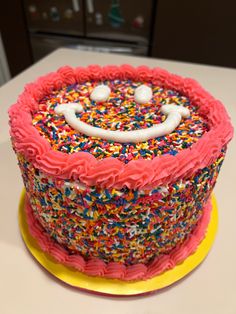 a birthday cake decorated with sprinkles and a smiley face