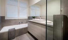 a bathroom with a sink, bathtub and window blinds in it's windows