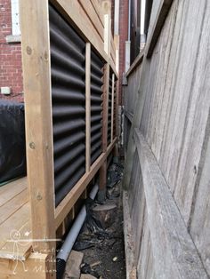 a wooden fence next to a building with pipes on the ground and wood slats around it