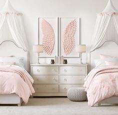 two white beds with pink comforters and pillows in front of them, one has an angel wing design on the headboard