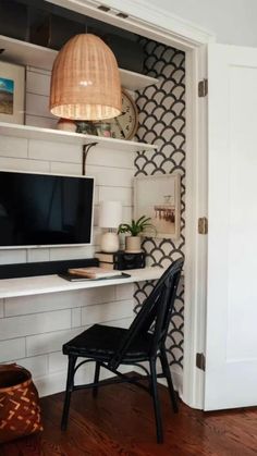 a room with a chair, desk and computer monitor on top of a shelf next to a door