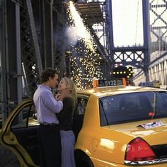 a man and woman standing in front of a taxi