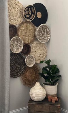 several baskets are hanging on the wall next to a potted plant