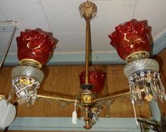 a chandelier with three red glass shades hanging from it's ceiling fixture