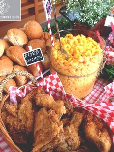 fried chicken, macaroni and cheese are on display at a buffet table with red checkered cloth