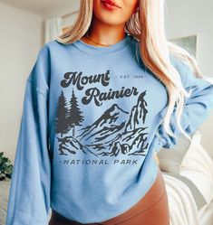 Mt. Rainier National Park Sweatshirt. Each one is printed to order using non-toxic inks and made under eco-friendly, sweatshop-free and ethical working conditions. A sturdy and warm sweatshirt bound to keep you warm in the colder months. A pre-shrunk, classic fit sweater that's made with air-jet spun yarn for a soft feel. This is a unisex sweatshirt, not fitted. Check the size chart for your perfect fit! ✦ 50/50 cotton/polyester ✦ Pre-shrunk ✦ Classic fit ✦ Reduced pilling and softer air-jet spun yarn ✦ Eco-friendly, Ethically Made & Sweatshop Free ✦ Printed to order with non-toxic ink ✦ 1x1 athletic rib knit collar, cuffs and waistband, with spandex ✦ Double-needle stitched collar, shoulders, armholes, cuffs and waistband ✦ Made to order: *Please allow 2-5 business days to print before be Fall Hiking T-shirt With Graphic Print, Outdoor Blue Sweatshirt With Letter Print, Blue Outdoor Tops With Screen Print, Blue Tops With Screen Print For Outdoor Activities, Blue Screen Print Tops For Outdoor Activities, Blue Screen Printed Tops For Outdoor Activities, Pre-shrunk Long Sleeve Tops For Outdoor, Fall Adventure Top With Graphic Print, Graphic Print Top For Adventure In Fall