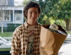 a young man holding a brown paper bag