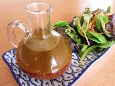 a glass pitcher filled with liquid next to a salad on a blue and white plate