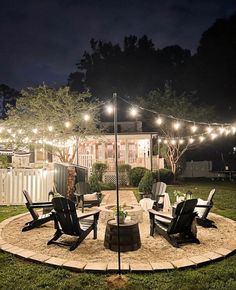 an outdoor patio with lights and lawn chairs in the middle of the yard at night