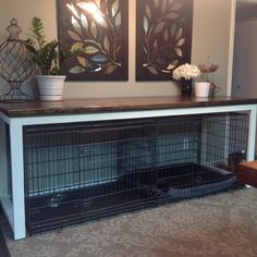 a large dog crate is sitting in front of two pictures on the wall with flowers