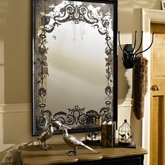 a mirror sitting on top of a wooden table next to a bird figurine