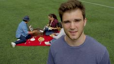 a man standing in front of a group of people sitting on top of a field