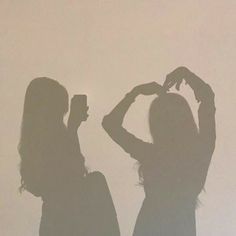 two women standing next to each other in silhouette