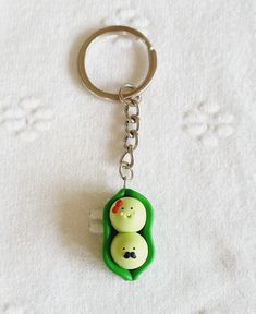 two peas in a leaf shaped keychain on a white surface