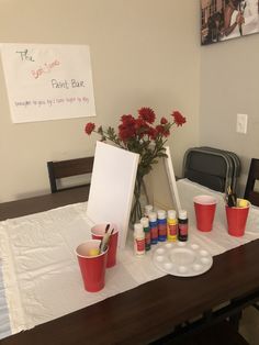 the table is set up with cups and paints