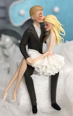 a bride and groom figurine sitting on top of each other