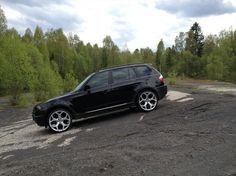 a black car parked in the middle of a dirt road