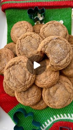 a pile of cookies sitting on top of a white plate next to a green and red christmas stocking