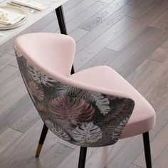 a pink chair sitting on top of a hard wood floor next to a white table