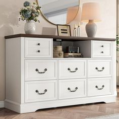 a white dresser with many drawers and a mirror on top of it in a living room