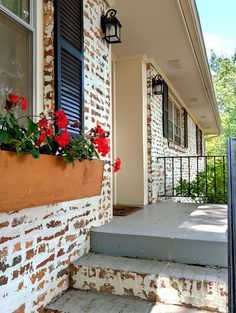 red flowers are growing in the window boxes on this front porch