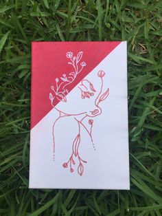 a piece of paper with a drawing of a woman's face on it sitting in the grass