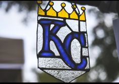 a stained glass window with the letter k in blue and yellow, hanging from a hook