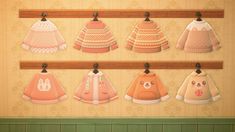 an image of baby sweaters hanging on a rack in a room with wallpaper