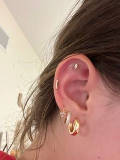 a close up of a person's ear wearing gold and diamond hooped earrings